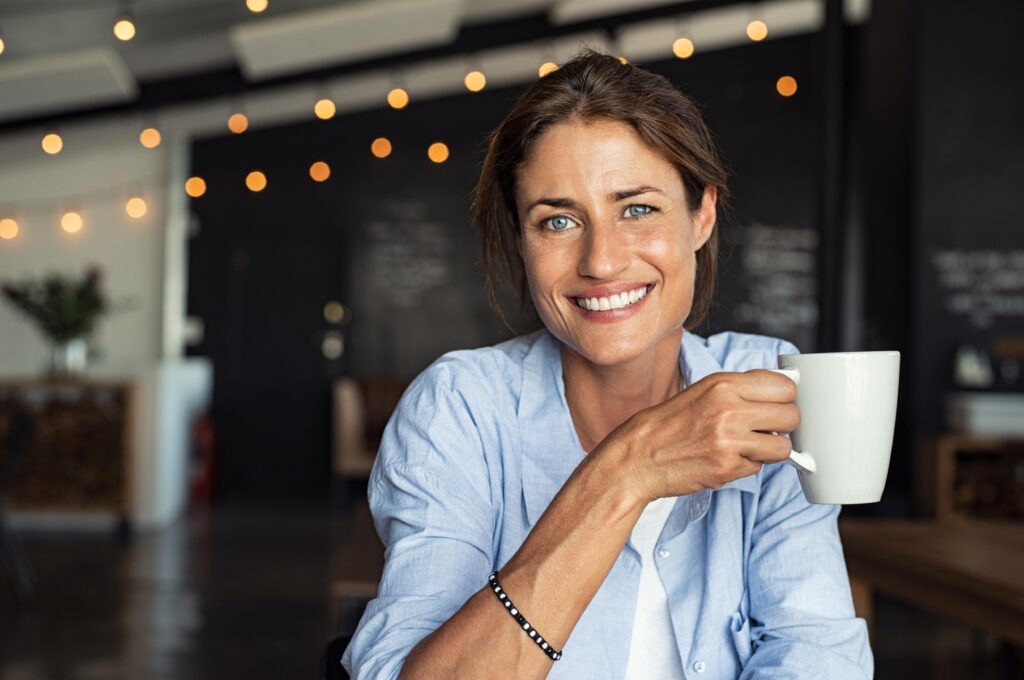 Woman smiling while enjoying cup of coffee